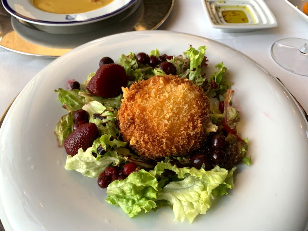 Salad of greens with berries soaked in. wine topped with fried cheese