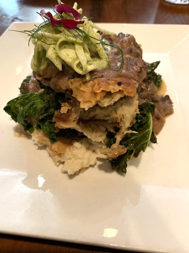 Stacked tower of cauliflower-potato whip, Seitan, greens and fennel salad