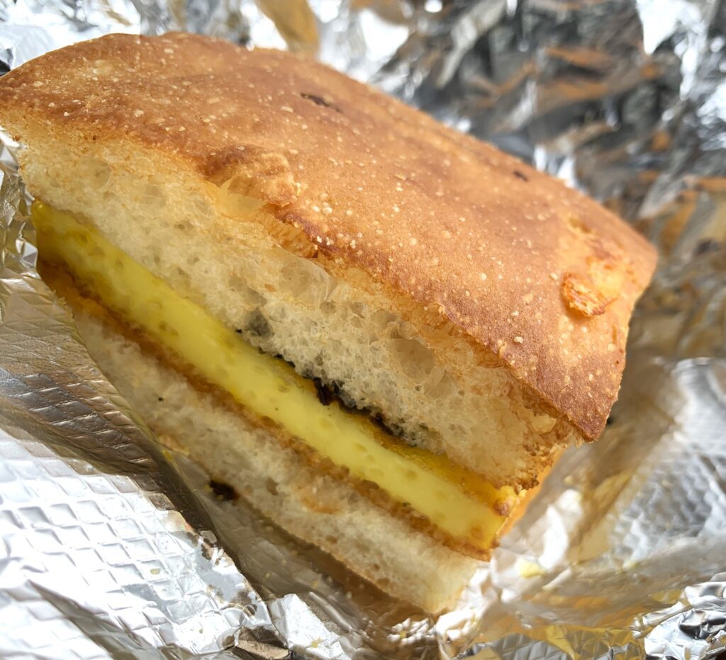 Breakfast sandwich wedge of steamed egg on focaccia-type bread.
