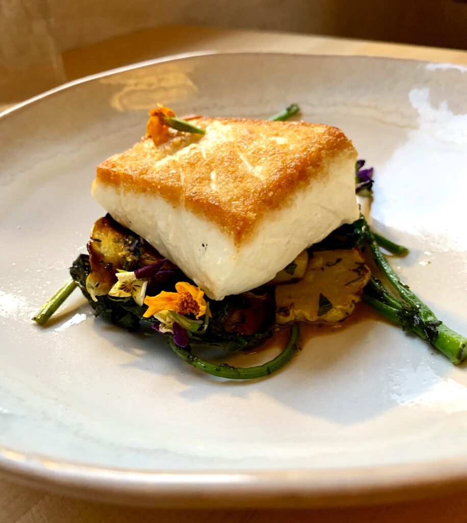 Piece of haddock served over broccolini.