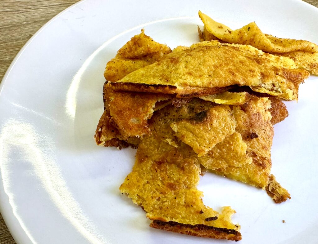 Broken up pieces of a large crepe, socca, on a plate